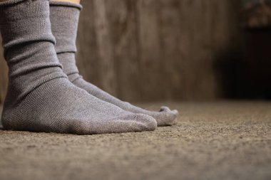 Mavi çoraplı ayaklar, gri bir halı, bir apartman dairesi, evde bir gün tatil.