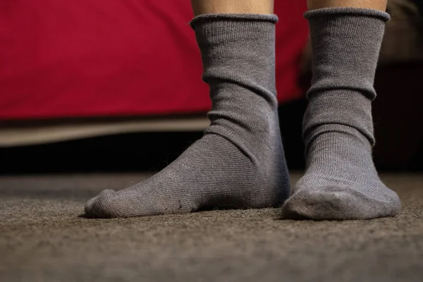 Mavi çoraplı ayaklar, gri bir halı, bir apartman dairesi, evde bir gün tatil.