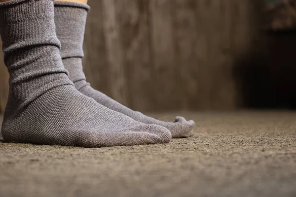 Mavi çoraplı ayaklar, gri bir halı, bir apartman dairesi, evde bir gün tatil.