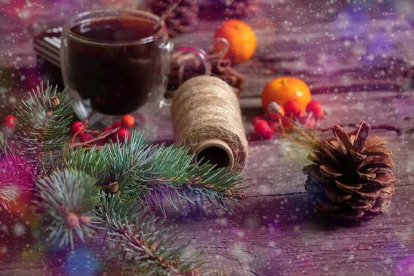 Une tasse de café avec des mandarines et une branche de pin sur une table en bois dans la lumière multicolore et éblouissement bokeh, décor du nouvel an — Photo