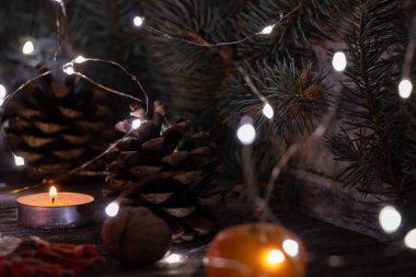 Yeni yıl sofrasında mumlar, çam dalı mandallı çelenk ve tarçınlı bir fincan, yeni yıl masa dekoru.