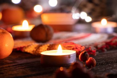 Yeni yıl sofrasında mumlar, çam dalı mandallı çelenk ve tarçınlı bir fincan, yeni yıl masa dekoru.