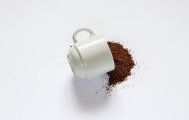 Beyaz arka plana serpilmiş kavrulmuş kahve ve yakın plan beyaz kahve fincanı.