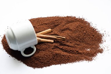 Beyaz arka planda üzerine kahve ve tarçın serpiştirilmiş beyaz fincan.