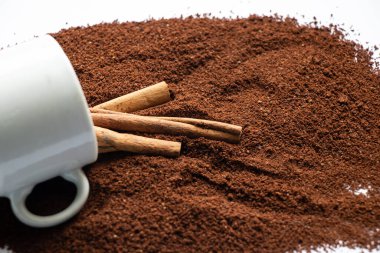 Beyaz arka planda üzerine kahve ve tarçın serpiştirilmiş beyaz fincan.