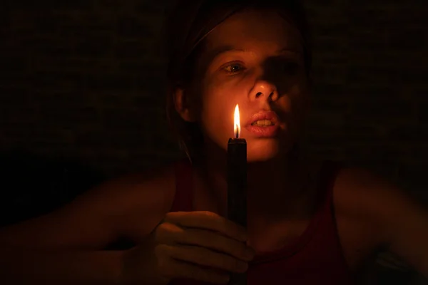 the girl's face in the dark against the background of a black burning candle