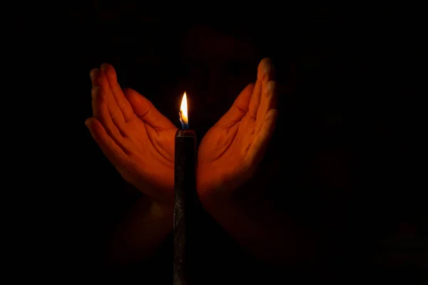 在黑暗中靠近一支黑色蜡烛的火焰时手拉手 — 图库照片