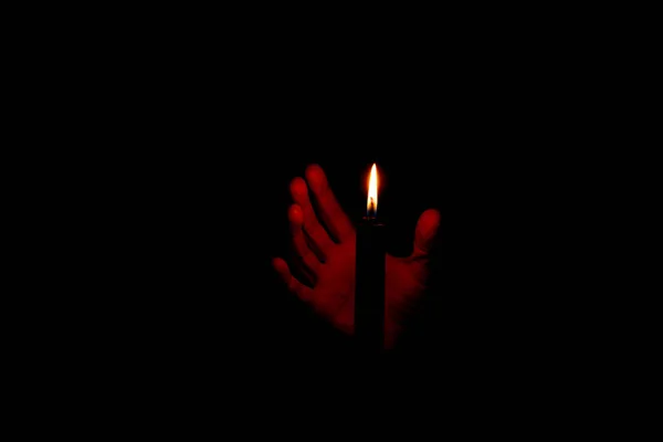 Main Dans Obscurité Près Flamme Une Bougie Noire Fermer — Photo