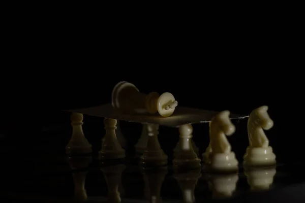 黒い背景の板に白いチェスの駒がありチェスをしています — ストック写真