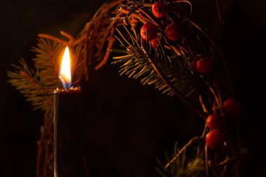 Yeni yıl çam çelenginin arka planında mum yakmak ve gece karanlığında viburnum.