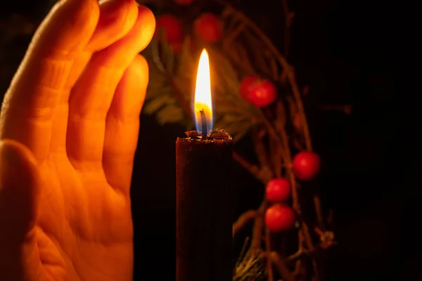 Frauenhand Neben Einer Kerze Auf Dem Hintergrund Eines Neujahrskranzes Dunkeln — Stockfoto