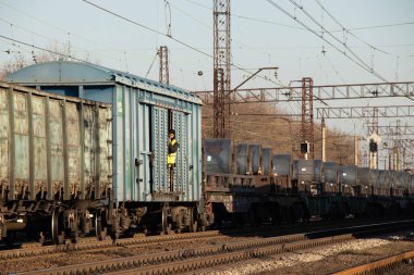 Ukrayna Dnipro 07.12.2020 - bir adam hareket halindeki bir yük treninin yük vagonundan, tren vagonunda çalışan bir işçiye bakar.