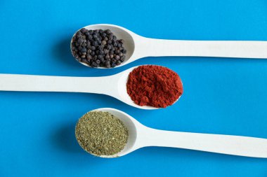 Farklı baharat ve biber çeşitlerine sahip ahşap kaşıklar izole bir arka planda yakın plan.