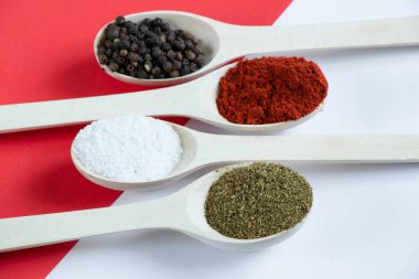 Farklı baharat ve biber çeşitlerine sahip ahşap kaşıklar izole bir arka planda yakın plan.