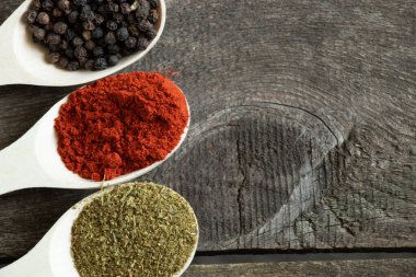 Ahşap arka planda farklı baharat ve biberli ahşap kaşıklar.