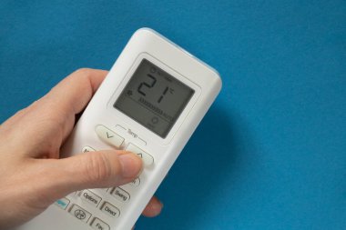 Kadın el düğmesi, izole edilmiş arkaplanda, beyaz klimanın uzaktan kumandasında.