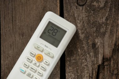 Tahta arka plandaki klimadan gelen beyaz uzaktan kumanda