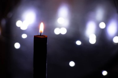 Karanlıktaki mum alevi bulanık çelenklerin arkasında Bokeh, din