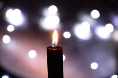 Karanlıktaki mum alevi bulanık çelenklerin arkasında Bokeh, din