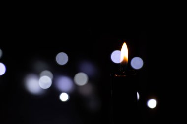 Karanlıktaki mum alevi bulanık çelenklerin arkasında Bokeh, din