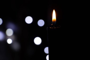 Karanlıktaki mum alevi bulanık çelenklerin arkasında Bokeh, din