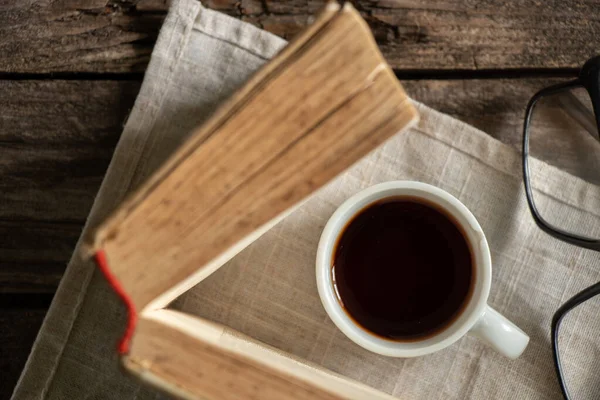 a cup of coffee book morning on a napkin on a wooden table next to glasses
