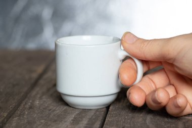 Kadın eli kafedeki ahşap bir masada küçük bir fincan kahve tutuyor.