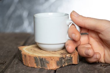 Kadın eli kafedeki ahşap bir masada küçük bir fincan kahve tutuyor.