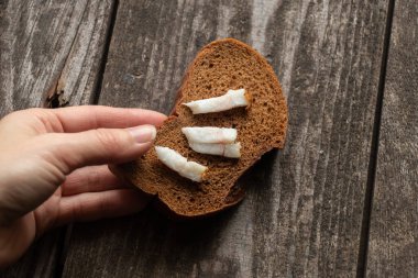 Kadın eli öğle yemeği için ahşap bir masada sarımsaklı bir parça siyah ekmek alır.