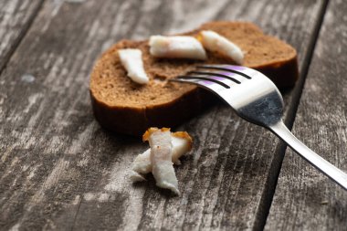 Domuz pastırmalı bir parça siyah ekmek ve öğle yemeği için ahşap bir masada çatal.