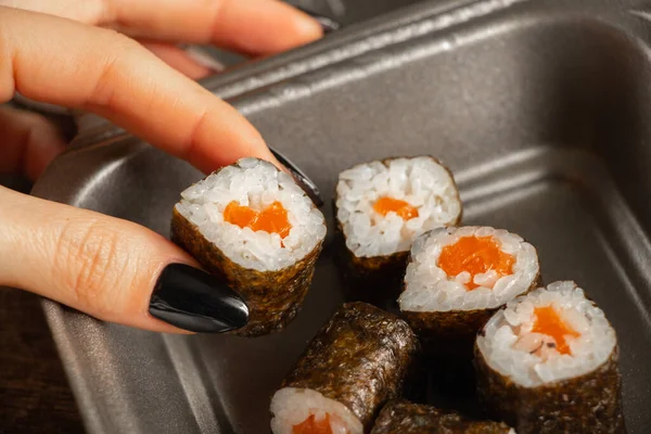 女性食指离开饭盒寿司与鲑鱼木制背景特写 餐馆食物 — 图库照片