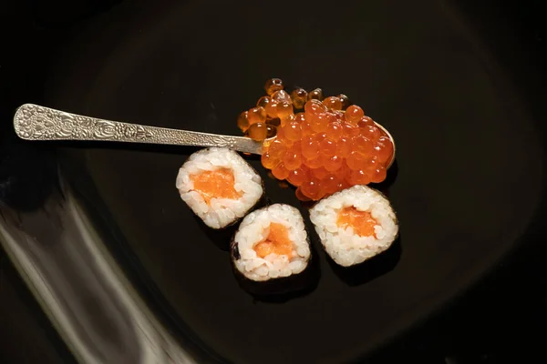 Sushi Lazaccal Vörös Kaviárral Egy Kanálban Egy Fekete Tányéron Közelkép — Stock Fotó