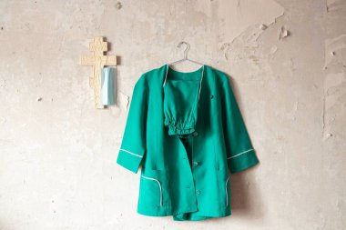 Ukraynalı hemşire kostümü, duvarda asılı. Kapalı bir Hıristiyan çarmıhının yanında.