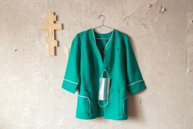 Ukraynalı hemşire kostümü, duvarda asılı. Kapalı bir Hıristiyan çarmıhının yanında.