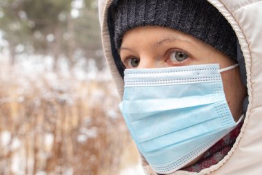 Kız kışı dışarıda tıbbi maskeyle geçirir.