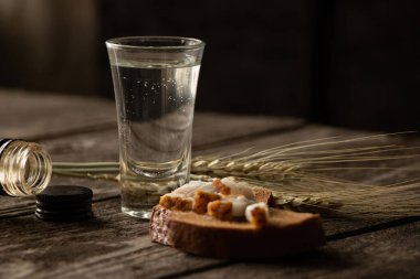 Karantina döneminde bir bardak siyah votka pastırmalı ekmek ve ahşap bir masada tıbbi maske.