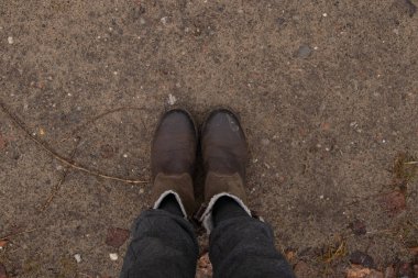 Gri pantolonlu kadın bacakları ve sonbahar öğleden sonra yürüyüş için ormanda yerde kahverengi botlar.