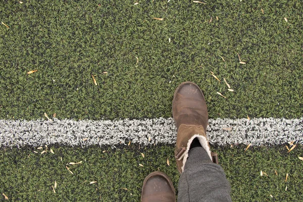 灰色のズボンと茶色のブーツを着た女性の足は緑の芝生の上に立ち — ストック写真