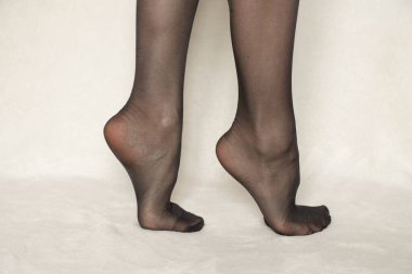 Beyaz halıda siyah naylon tayt giymiş kadın bacakları.