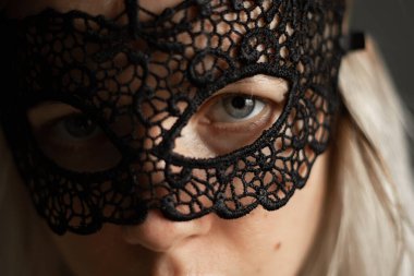 Karnaval dantel maskeli bir kızın yüzü, karanlıkta.