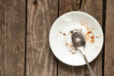 Yemekten sonra bir çay kaşığıyla ahşap bir masada kirli bir tabak.