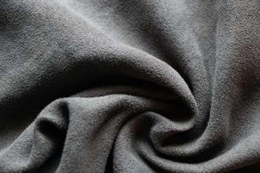 Arkaplanda yakın plan olarak koyu gri yumuşak buruşuk kumaş