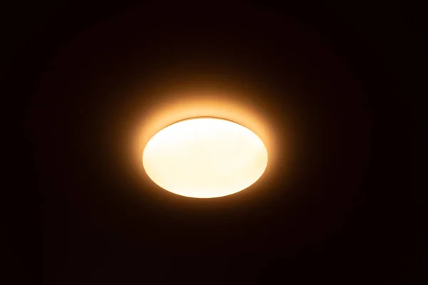 Okrągły Płaski Żyrandol Ciemnym Suficie Domu Świeci Jasnożółtym Światłem — Zdjęcie stockowe