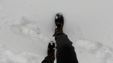 Kahverengi çizmeli kız kışın karda yürüyor.