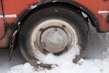Eski araba tekerleği kışın yolda, karlı yolda. Kapatın.