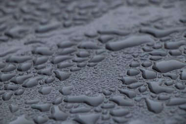 Siyah metal zemine su damlaları düşüyor. Yakın plan.