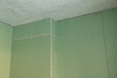 Yenileme sırasında bir odada yeşil alçıdan duvar, bir dairenin yenilenmesi, arka plan olarak alçı pano, bir apartmanda yenileme.