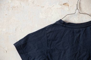 Koyu mavi tişört askılarda Eski beyaz bir duvarda