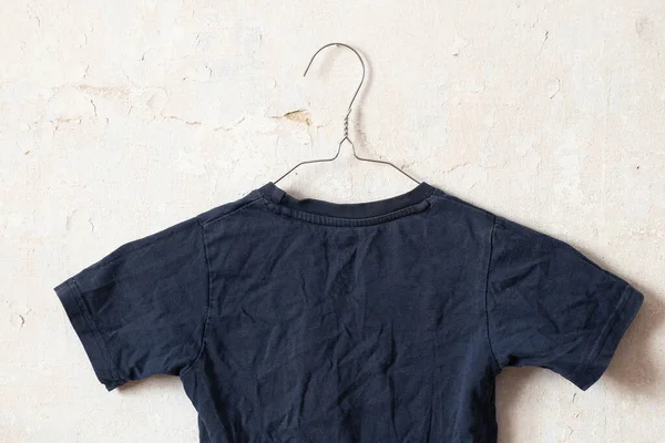 dark blue t-shirt on hangers on an old white wall like moket