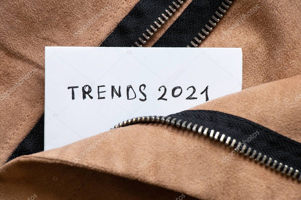 Inscription on a sheet of white paper trends 2021 in the pocket of a brown zipped jacket